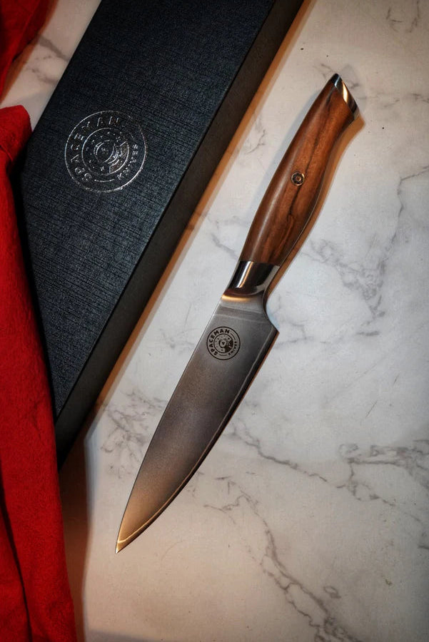 Knife with wooden handle on a marble surface next to a black box with a logo.