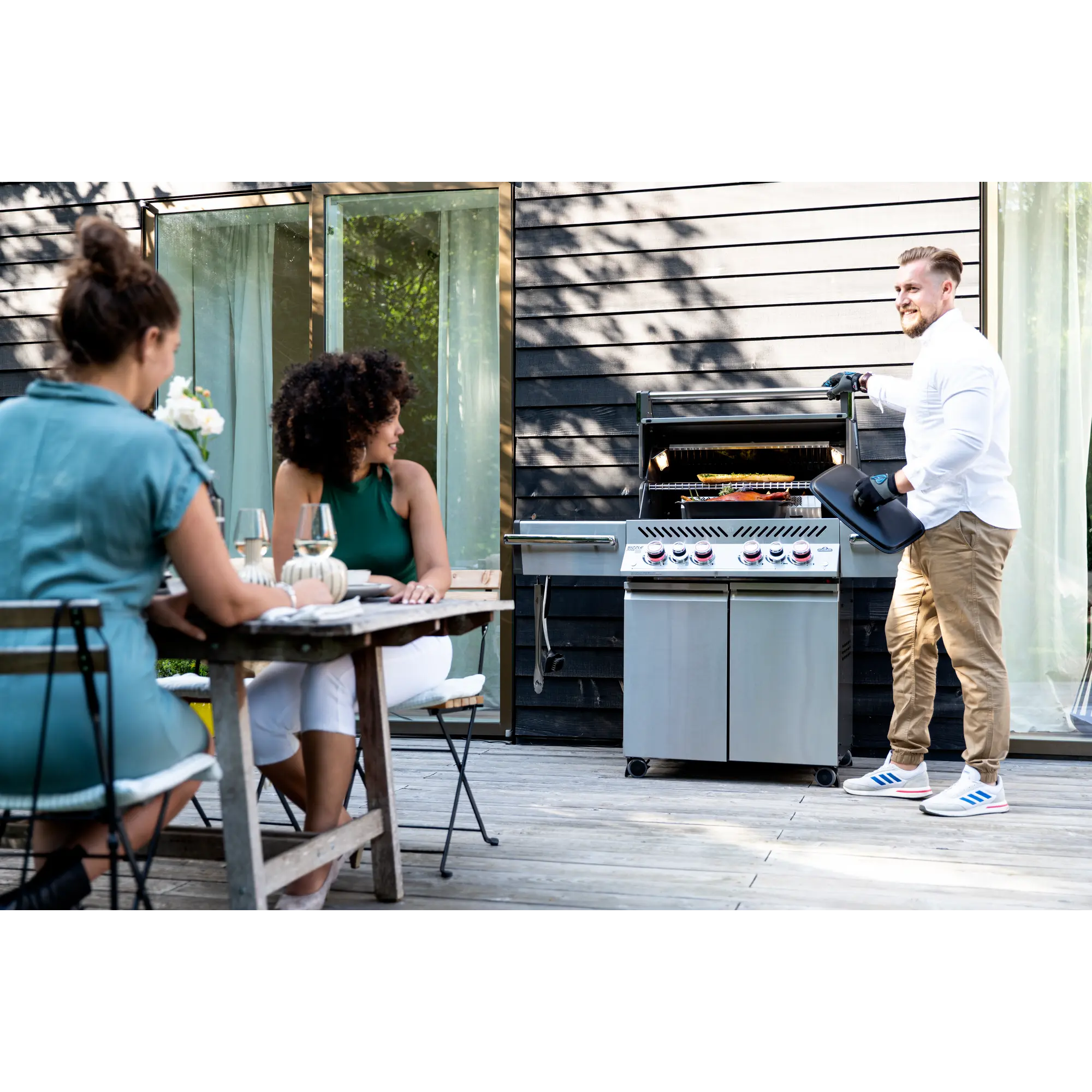 Folks sitting on a backyard deck around a Napoleon Grill BBQ for dinner