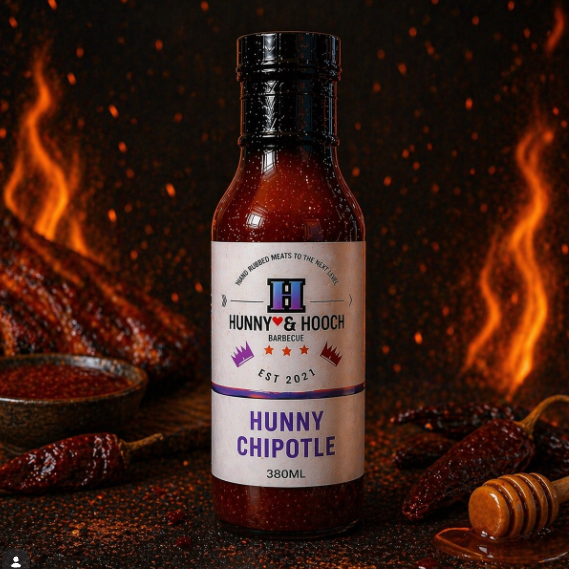 bottle of hunny chipotle with flames and peppers on a black background