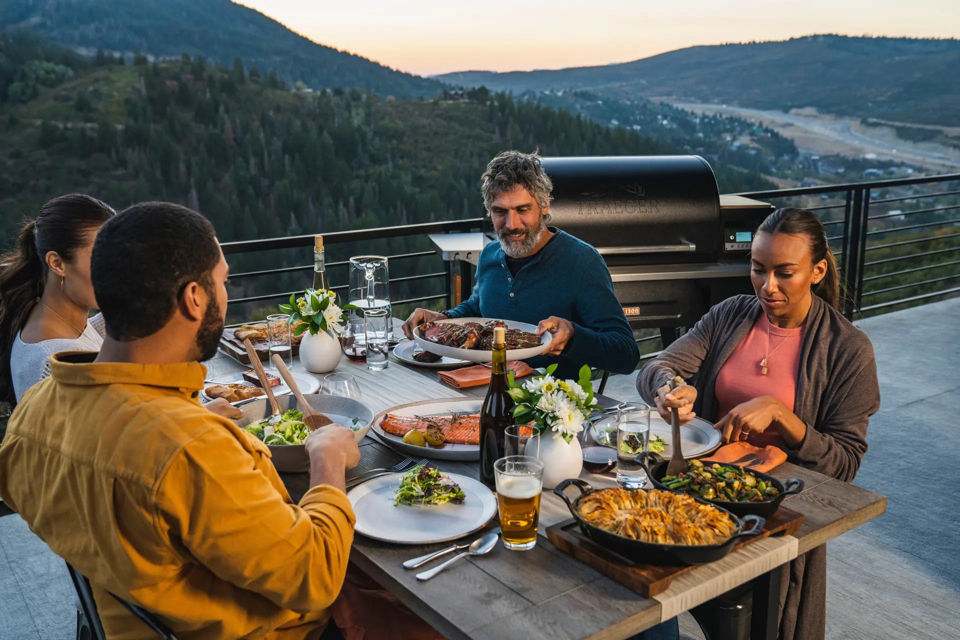 Friends Eating a BBQ feast with a Traeger Grill behind them