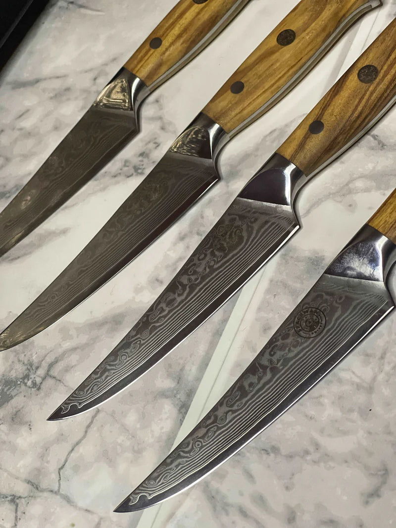 Set of four steak knives with wooden handles on a marble surface