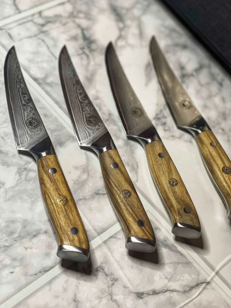 Set of four knives with wooden handles on a marble surface
