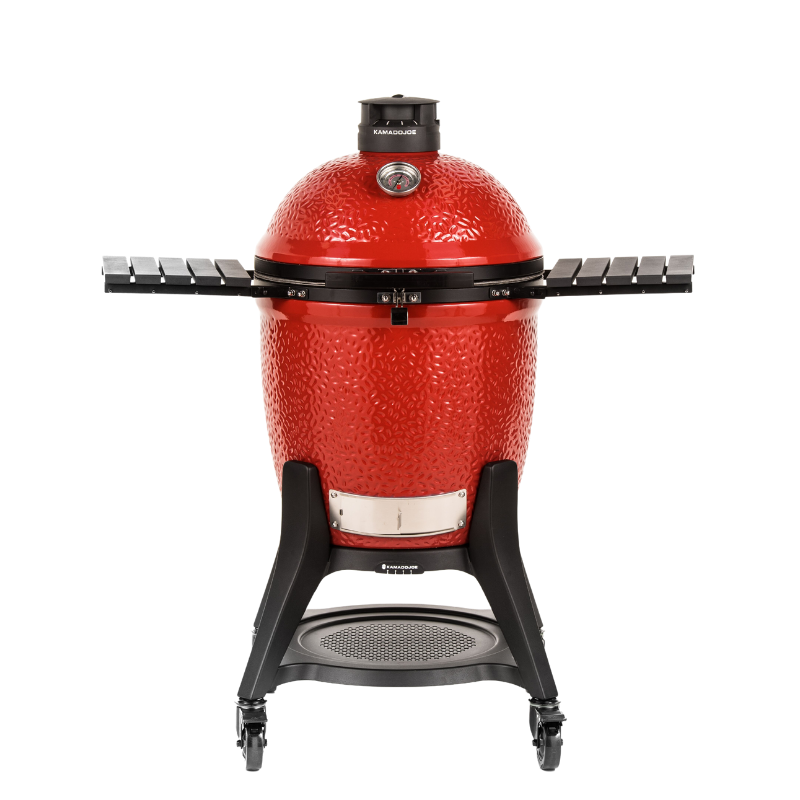 Large, red, dome-shaped charcoal grill with shelves on both sides and a thermometer and vent on the lid